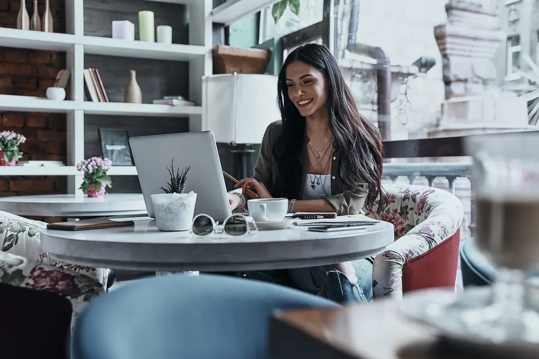 A woman working on a laptop at a table in a coffee shop