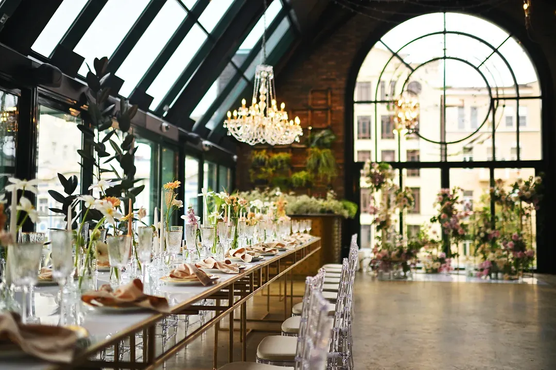 A long banqueting table laid for a wedding under chandeliers