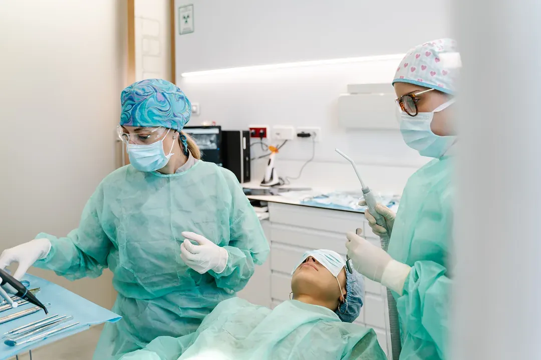 A dentist and hygienist in scrubs working together on a patient
