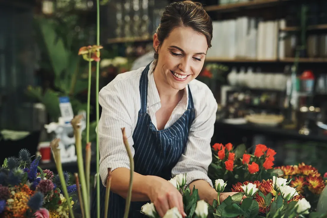 A florist arranging a bouquet at the bench in her shop